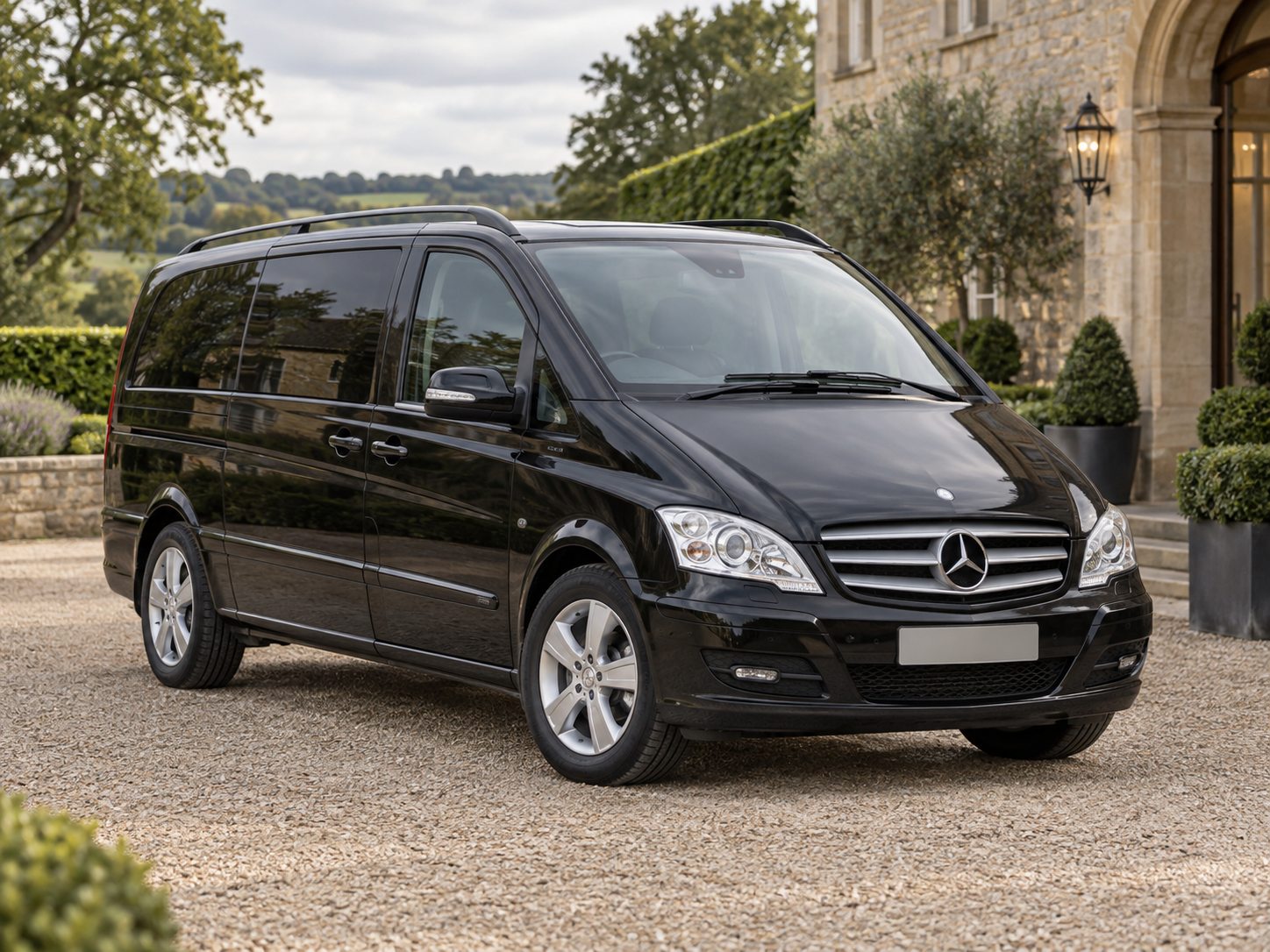 Illustrative black Mercedes Viano passenger vehicle outside a stone hotel